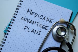 Concept of Medicare Advantage Plans write on book isolated on Wooden Table.