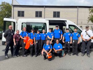 A group poses for a photo in front of an ambulance.